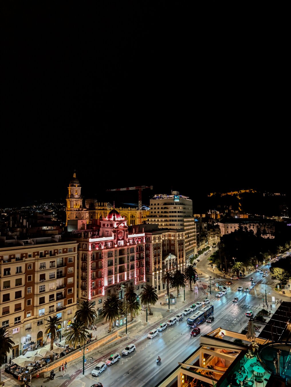 Night view of the Alameda Principal of Malaga, there is a strong contrast between th light of the city buildings and the dark of the background.