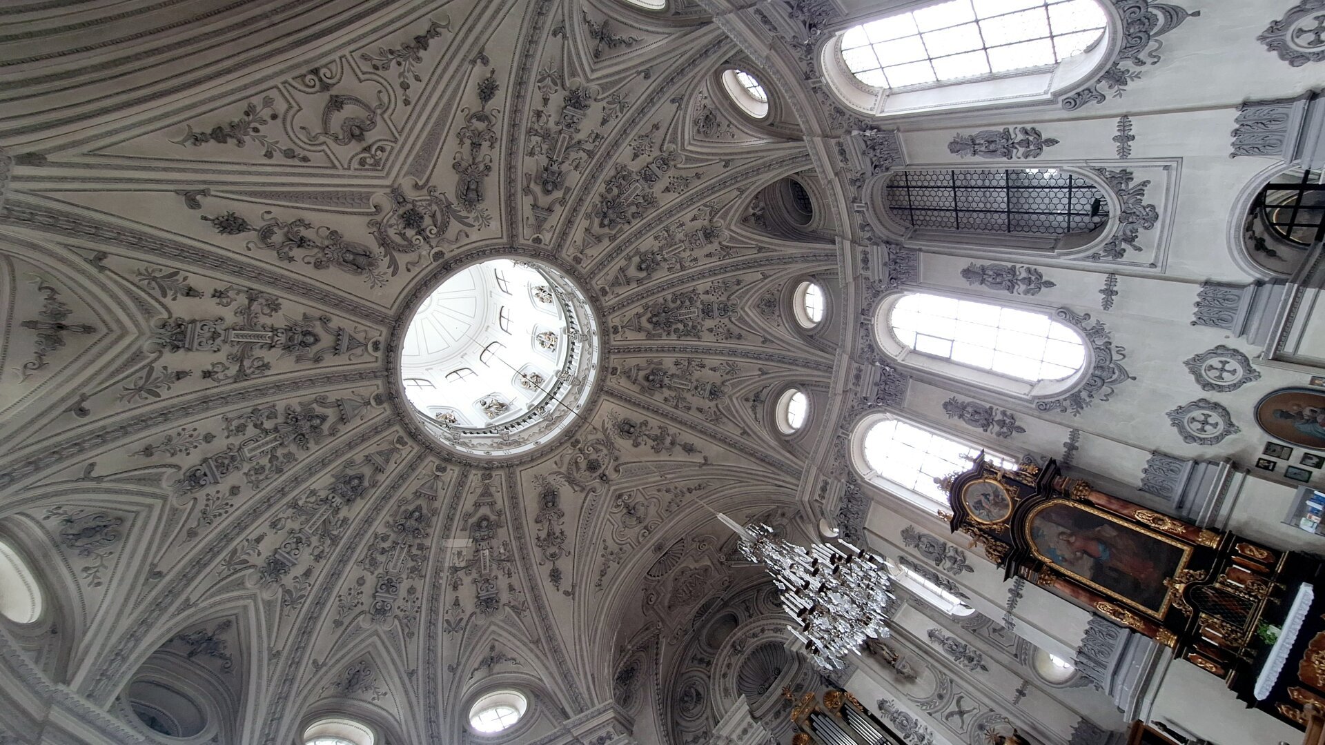 Inside of the dome of a church, white, grey and blue with geometrically placed windows.