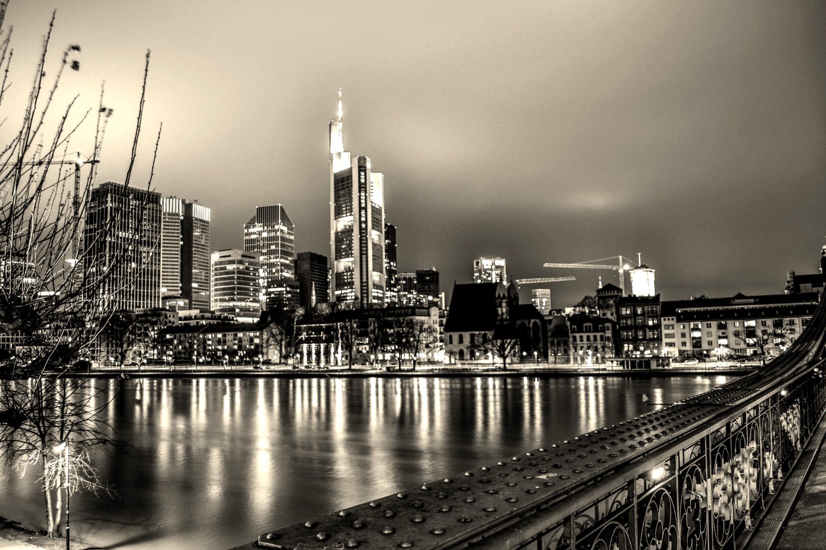 Skyline Frankfurt bei Nacht in schwarz-weiß, die Gebäude spiegeln sich im Main