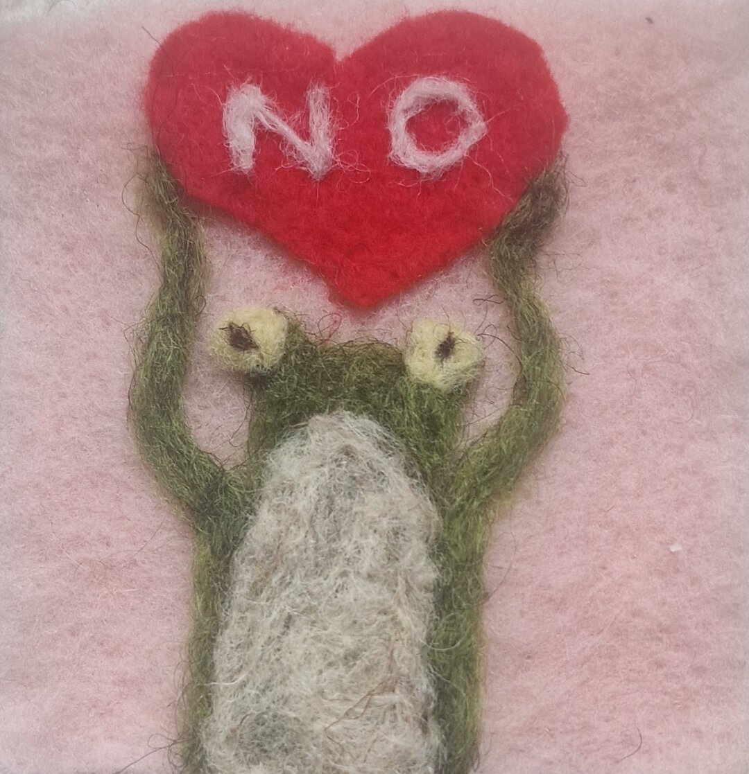 A frog holding a red heart with the word NO on it in white writing.