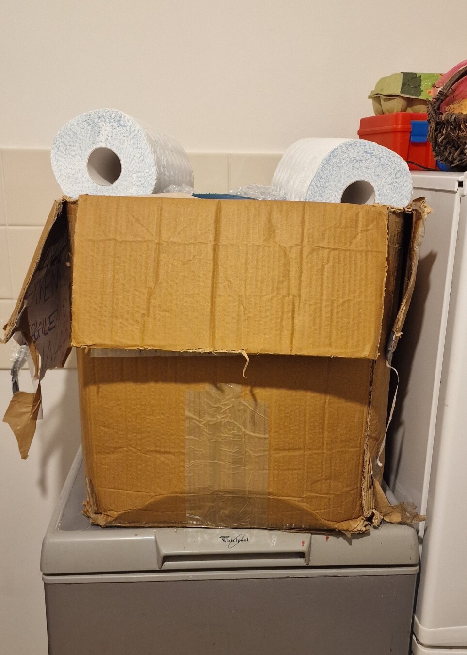 A cardboard box with two kitchen  towels on it so they form a face