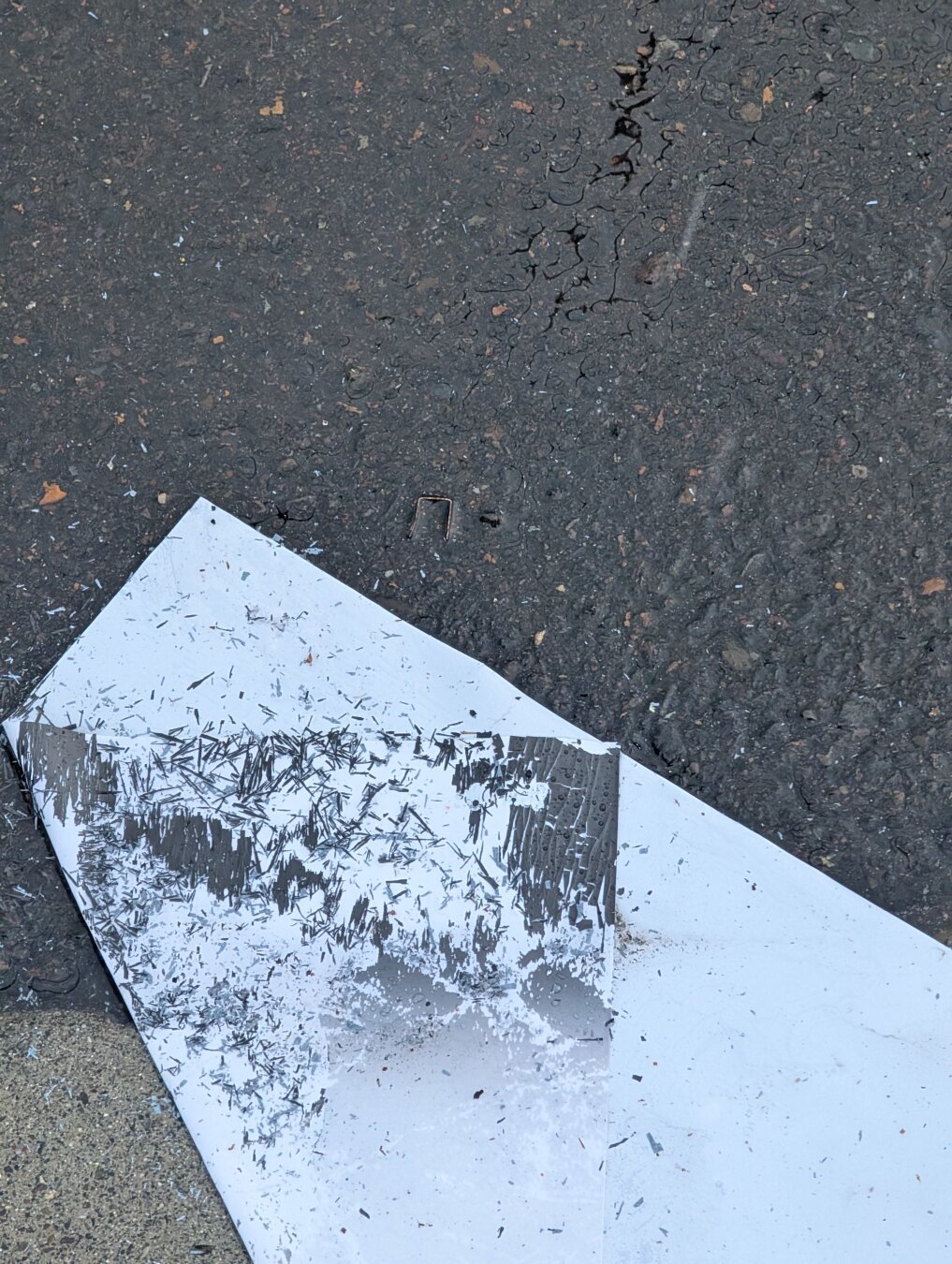 Folded white paper marked black on the ground