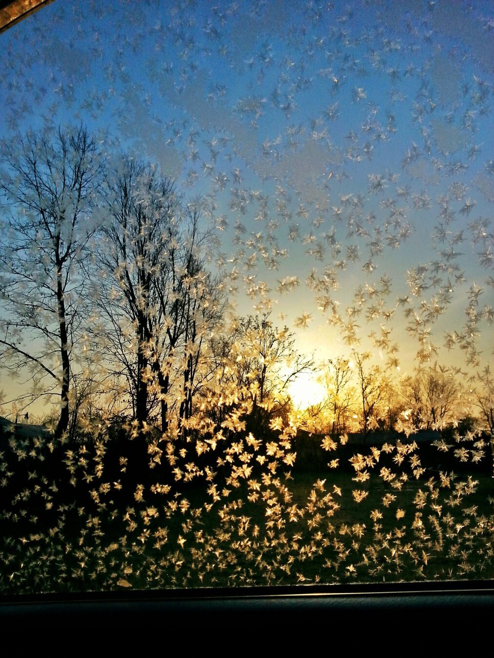 photo is of a frozen passenger window, with sunrise shining through.