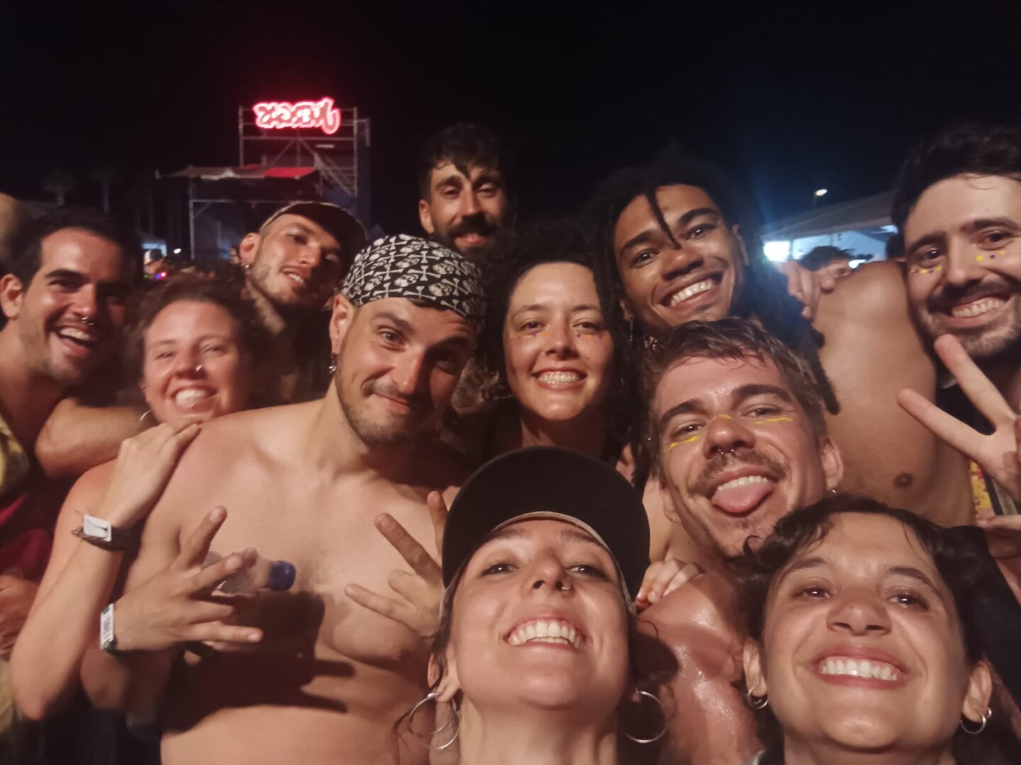 Un grupo de gente sonriendo, mostrando signos de emoción en un festival, algunos de ellos, llevando pintura ornamental en la cara