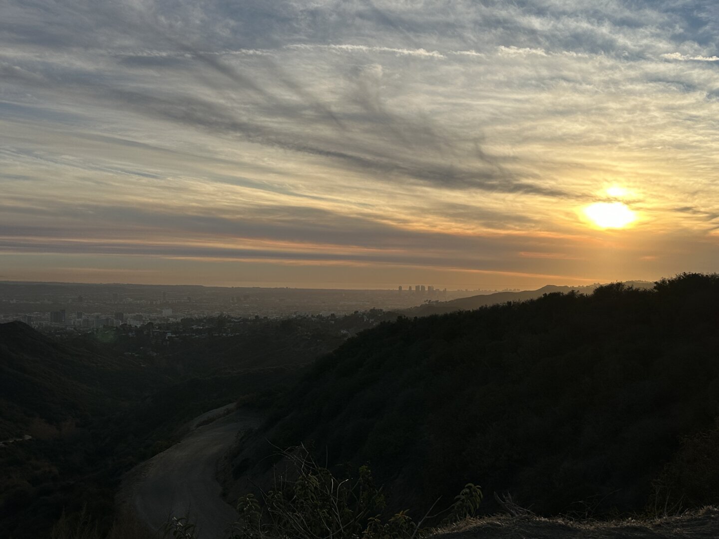 Nearly sunset from the top of Trash Truck in Griffith Park. Sweeping clouds and orange smoke haze.