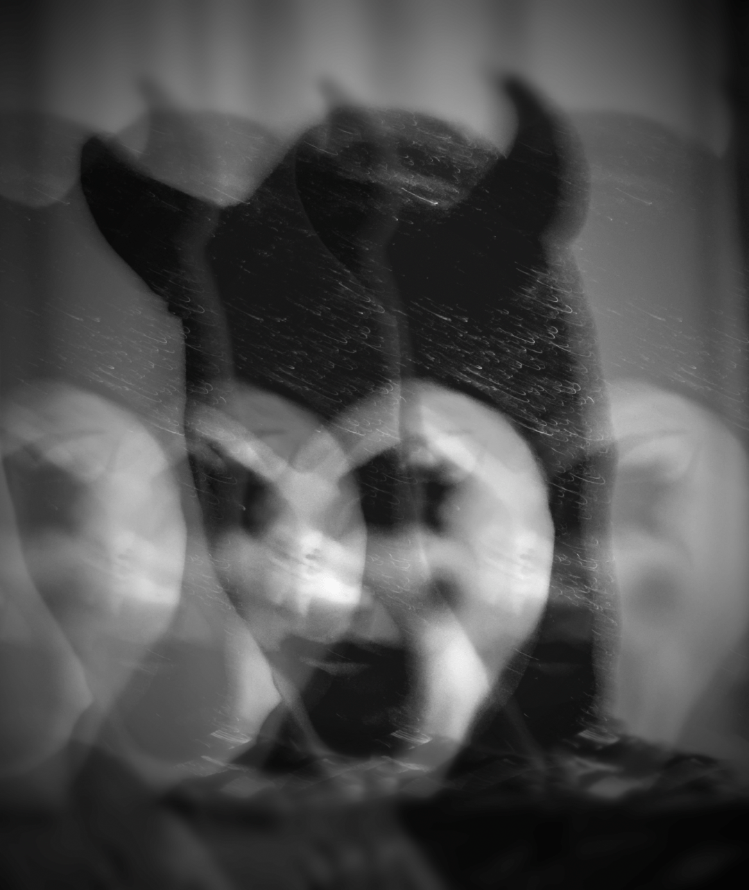 black and white image of a distorted devil face caked with circus makeup.