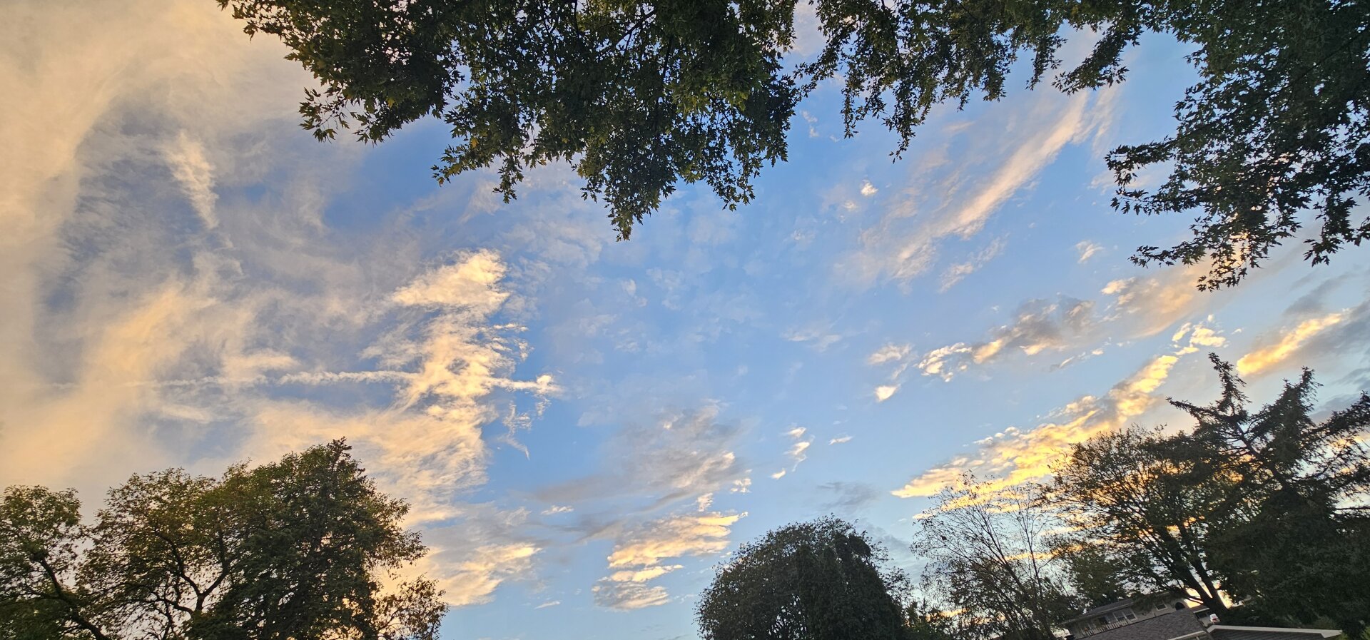 photo taken of the sky at dusk, partly cloudly. the sun shines through the clouds, giving the appearance of gold-colored clouds