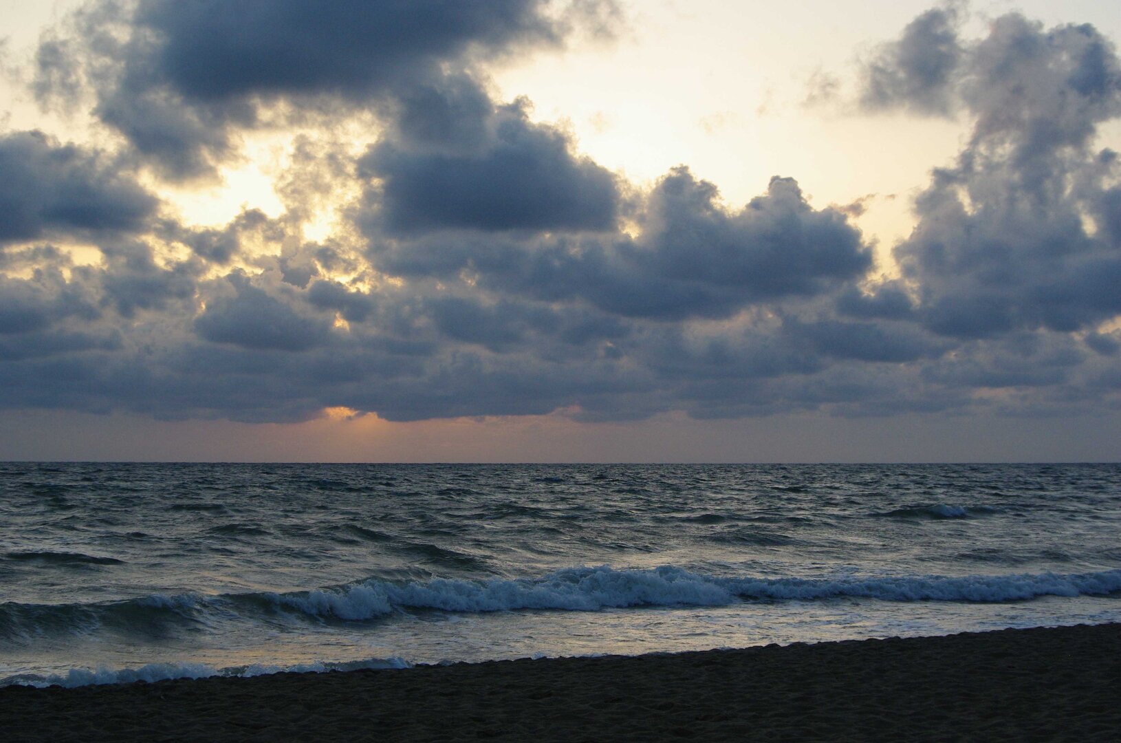 Clouds and waves rolling in at sunset.