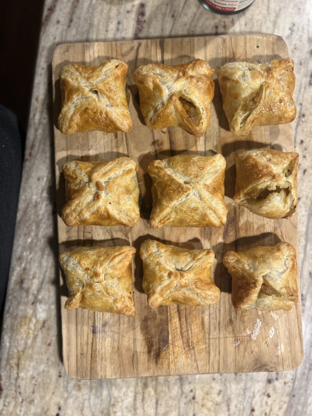 9 baked samosas on a wooden cutting board