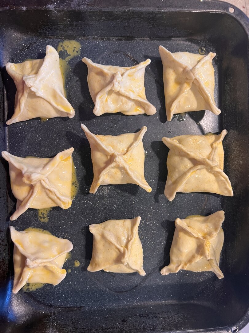 Nine raw samosas on a baking sheet