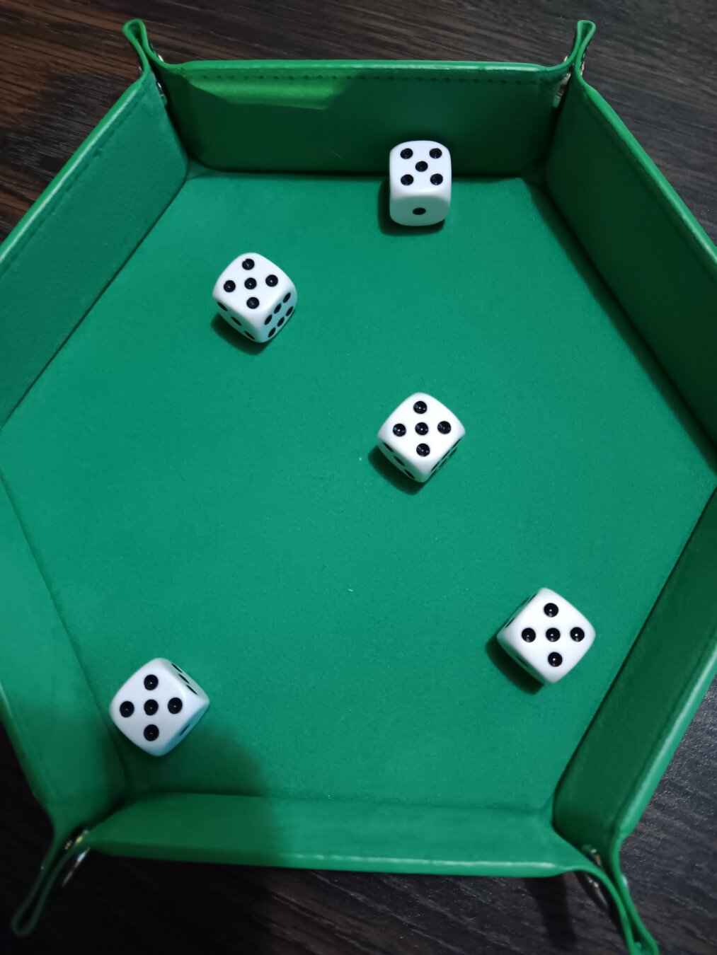 A green hexagonal dice tray holds five white d6, each with the 5-pip side up.