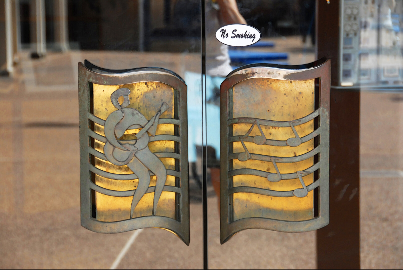 door handles with what is probably supposed to a musical sheet on the right, and Elvis art on the right. about the handles in a no smoking sticker