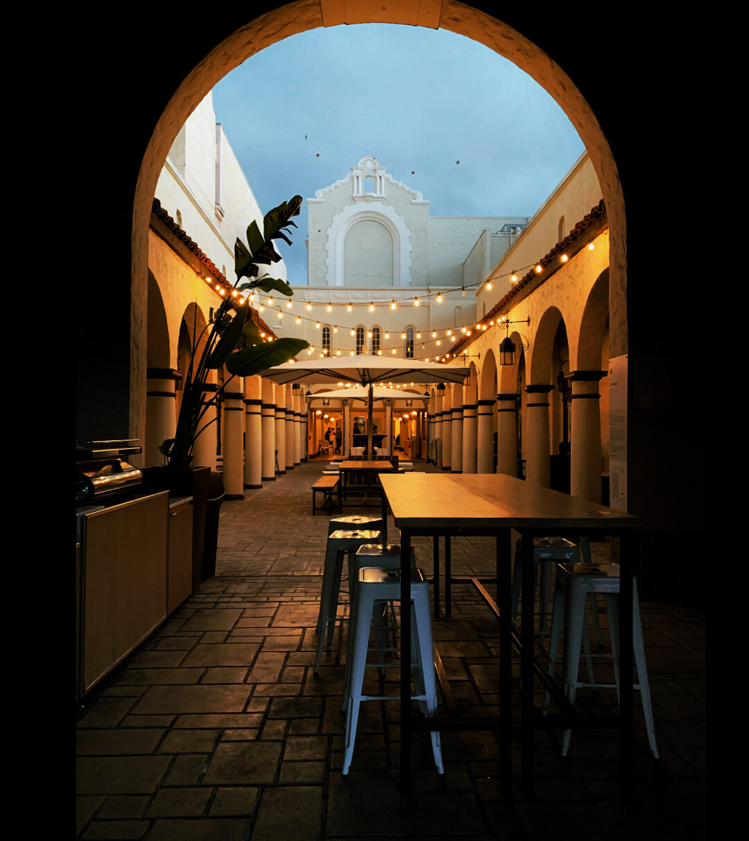 The sun and some indoor light on arches in a patio - there's a table in the front