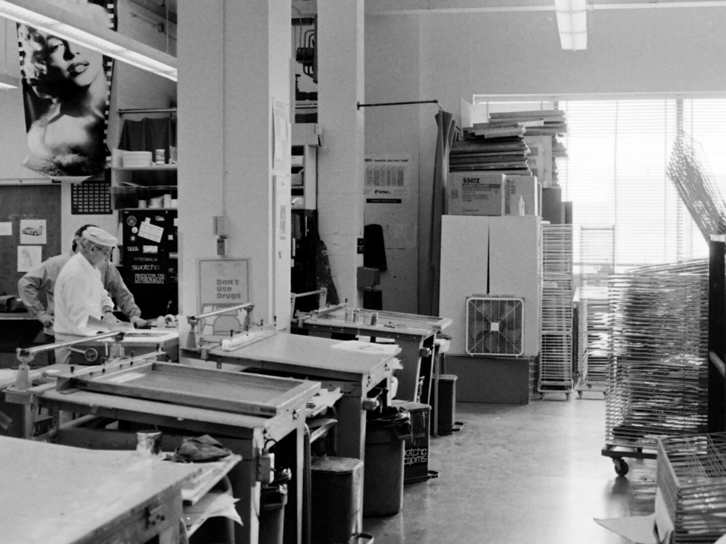 black and white interior photo of a workshop with two people in the background working