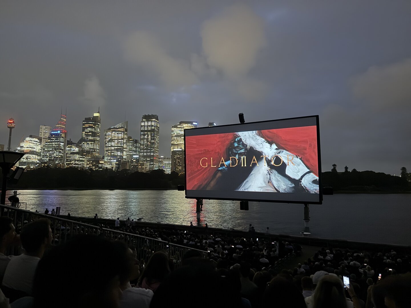 A photo taken at night in Sydney at Lady McQuarrie’s chair of the open Air cinema screen with the Sydney skyline in the background