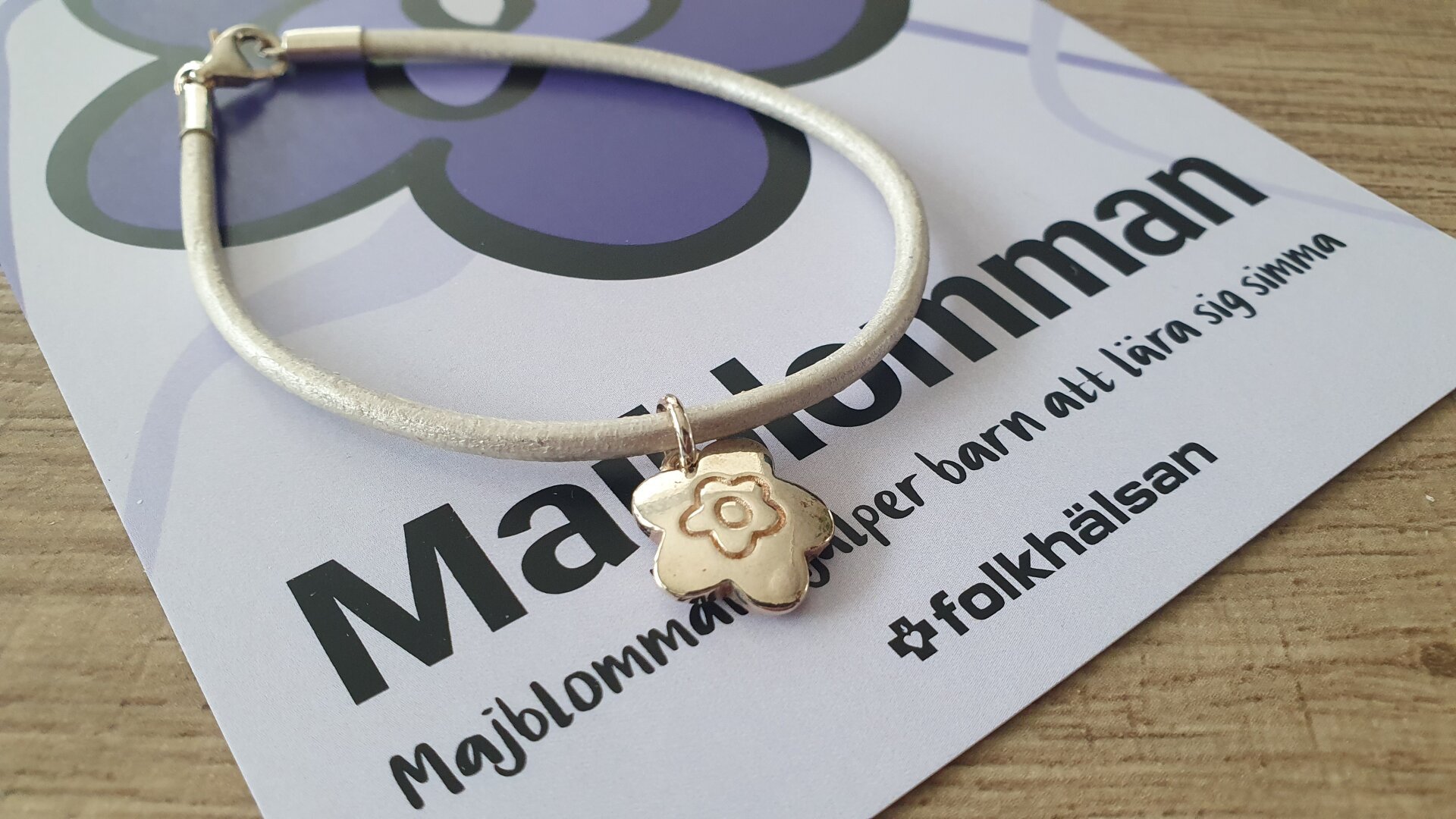 Ett fint armband med ett smycke som ser ut som majblomman.