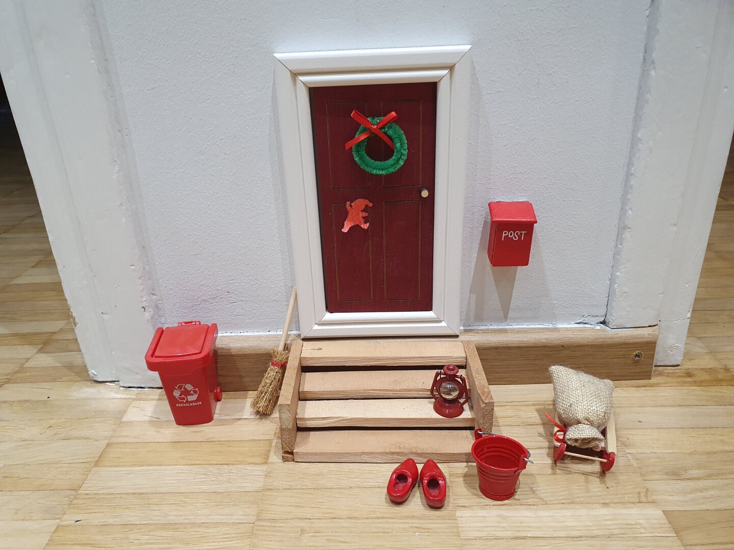 En liten nissedörr, med rekvisita runt omkring. Bl.a. träskor, släde och postlåda.