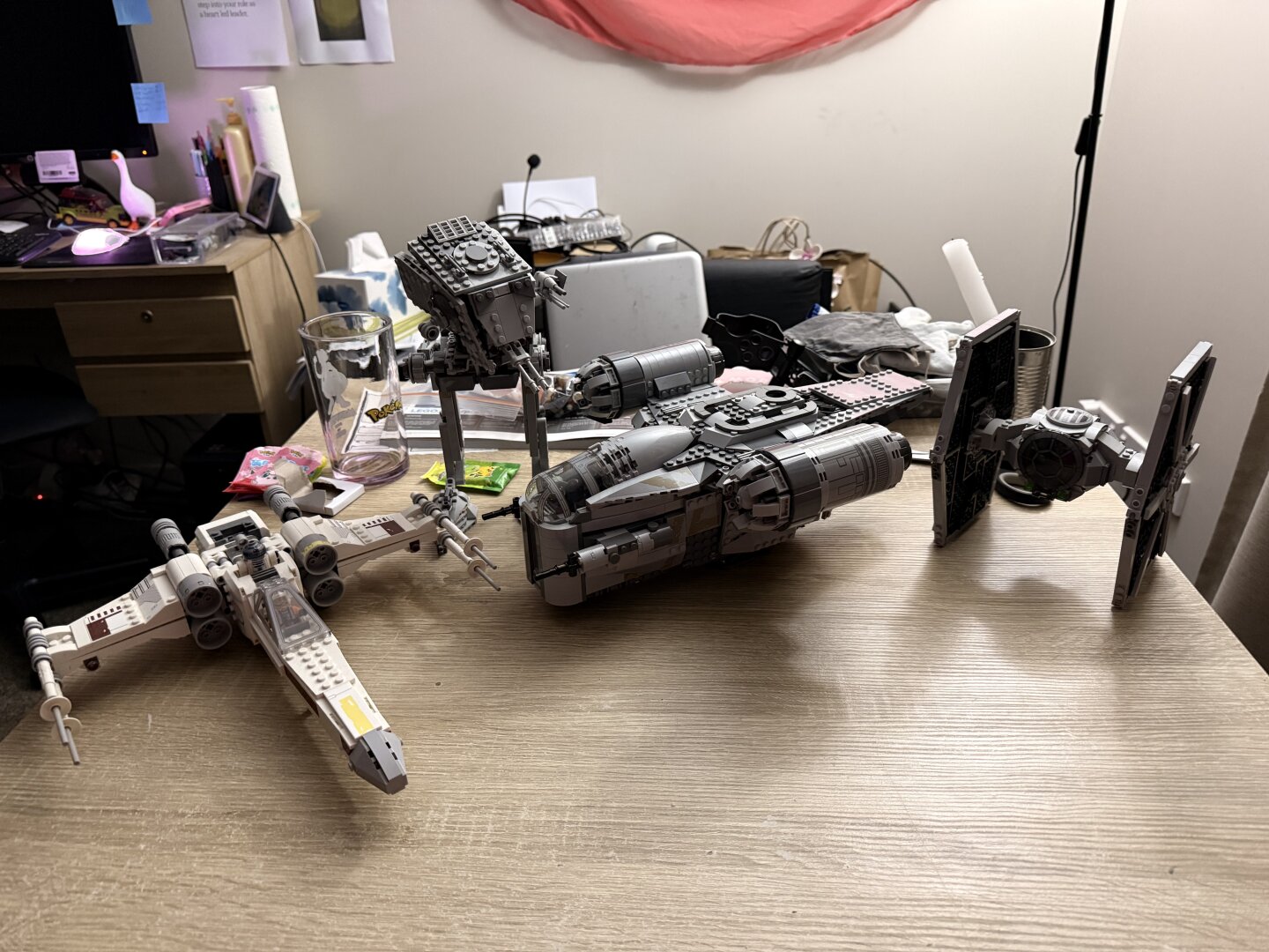 the completed razor crest ship but to its right is a lego TIE fighter, and on its left is lego luke skywalker’s x-wing, then behind the cabin a little is the AT-ST