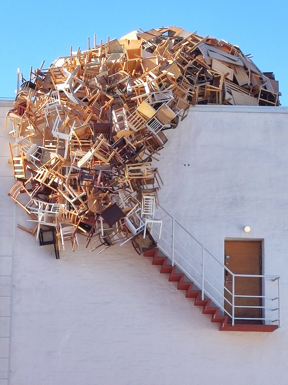 art installation : many chairs hanging on the side of a buildng (the museum) looking like a giant tongue