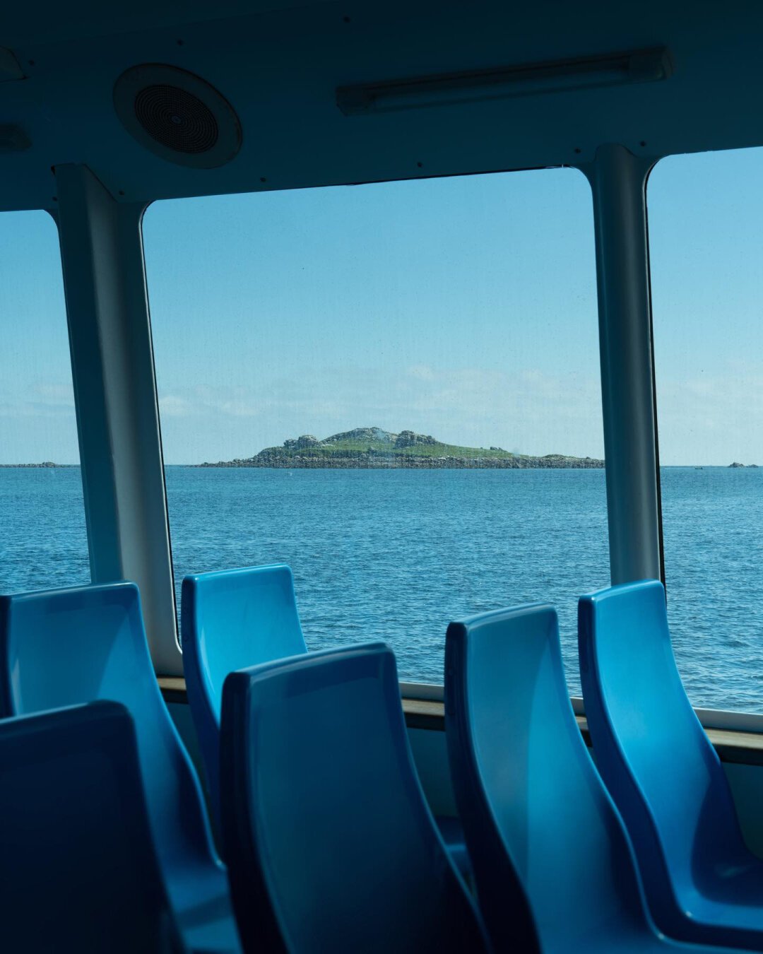 View of an island from inside a boat with empty bleu seats