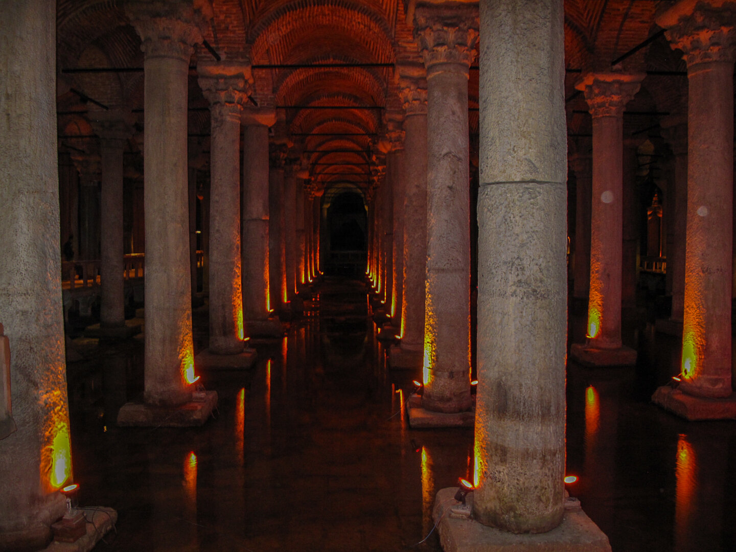 Dimly lit underground hall of the Basilica Cistern in Istanbul, Turkey, with rows of stone columns reflected in water.
