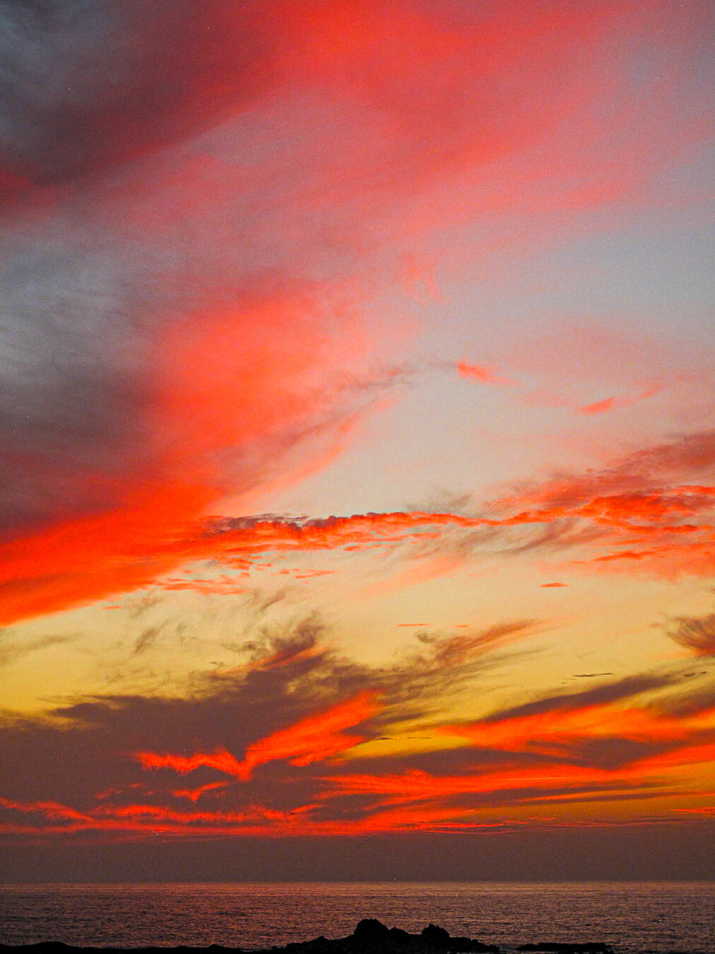 Clouds glowing in warm  sunset colours above the Atlantic coast near Essaouira, Morocco. Soft golden, orange and pink light illuminates the sky, creating a dramatic seascape and a tranquil coastal atmosphere.