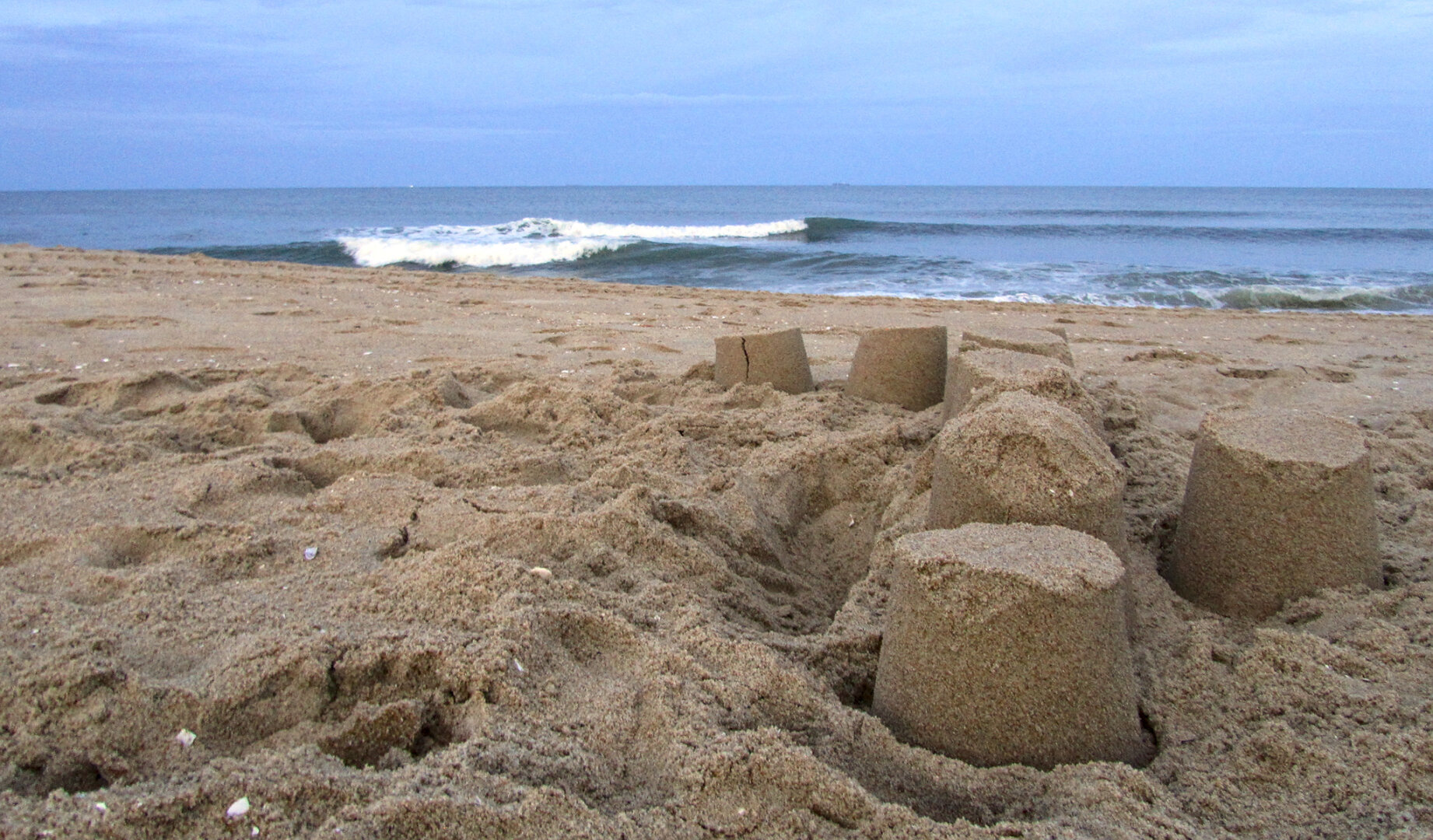 abandoned sandcastle on the beach with the ocean in the background