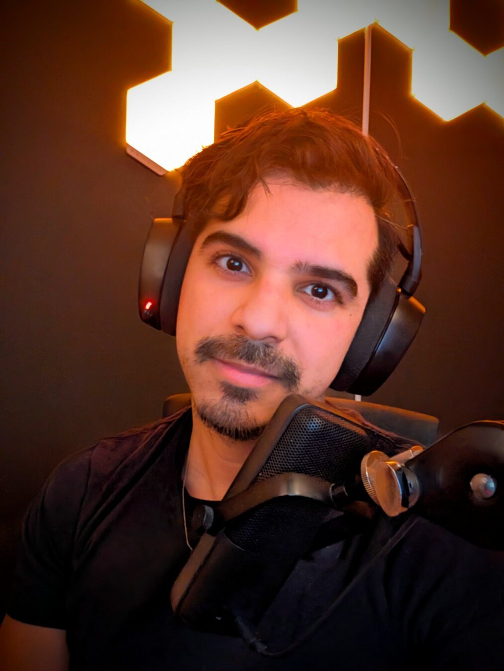 Selfie of me with gaming headset on and by hexagon lights behind me