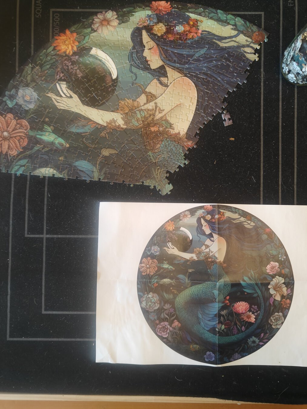 A partially complete round puzzle of a mermaid surrounded by water and flowers