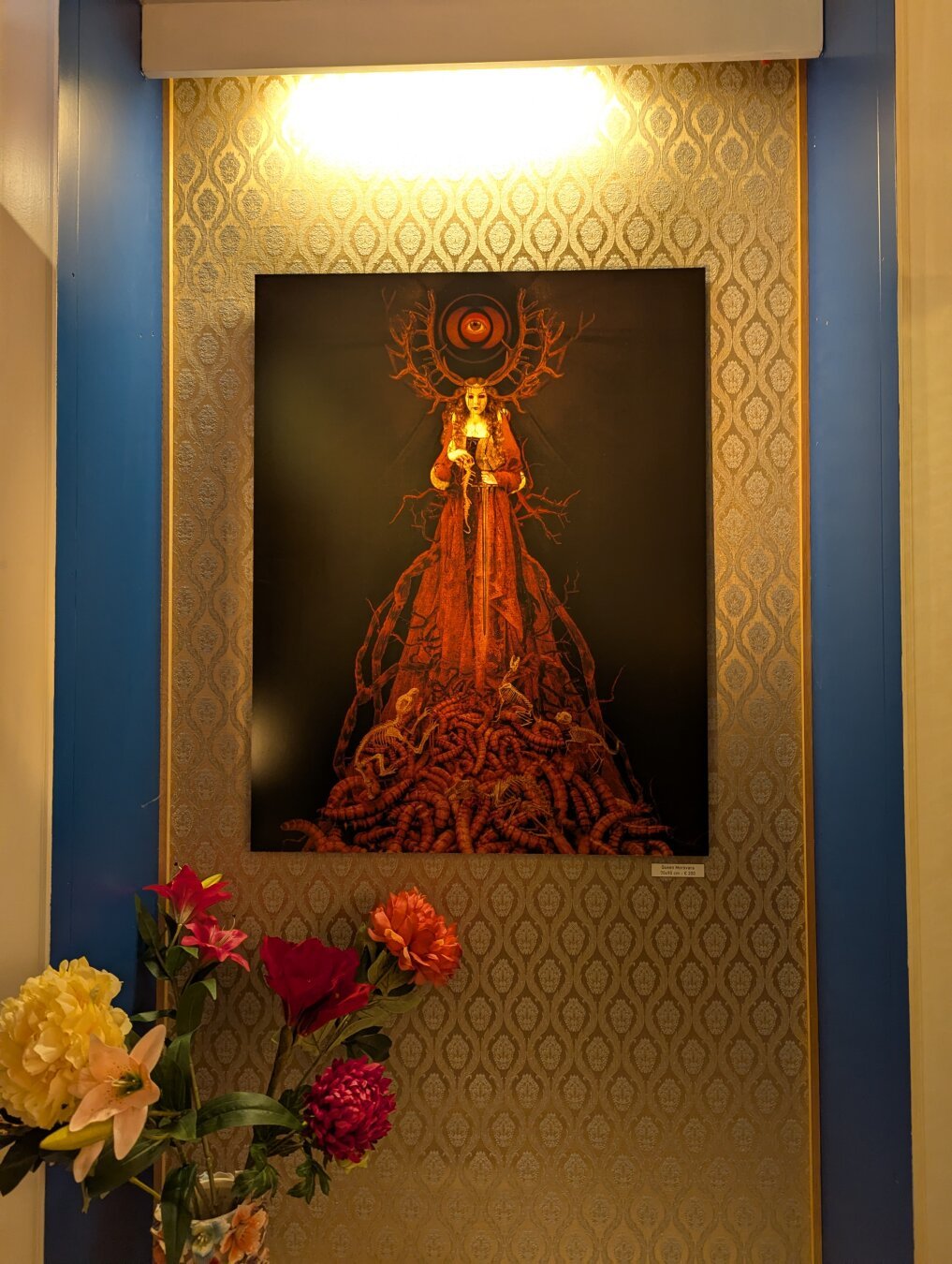 Creepy artwork depicting a woman with antlers in a red dress standing in a pile of enormous maggots