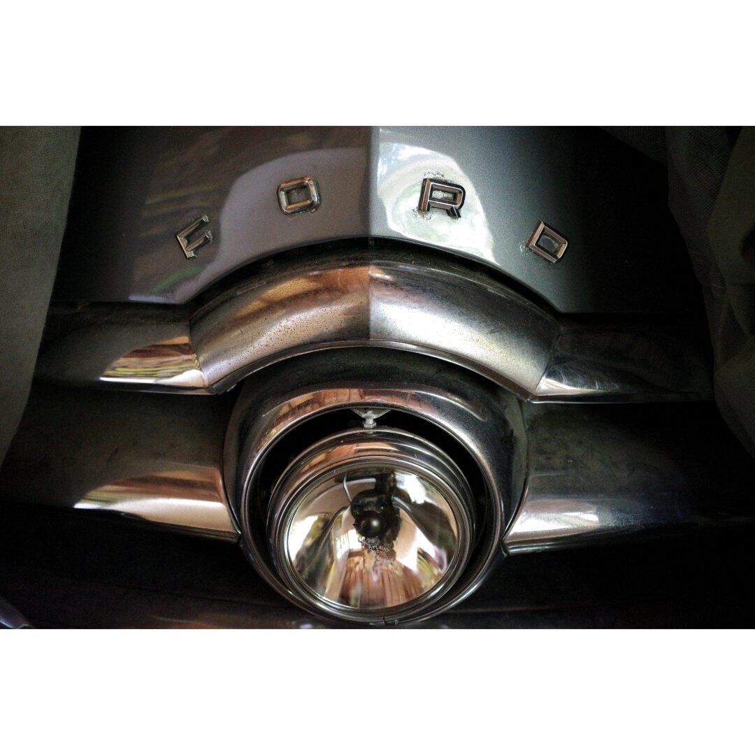 Front of a grey 1949 Ford sedan with the central billet grill replaced by an articulating headlamp.