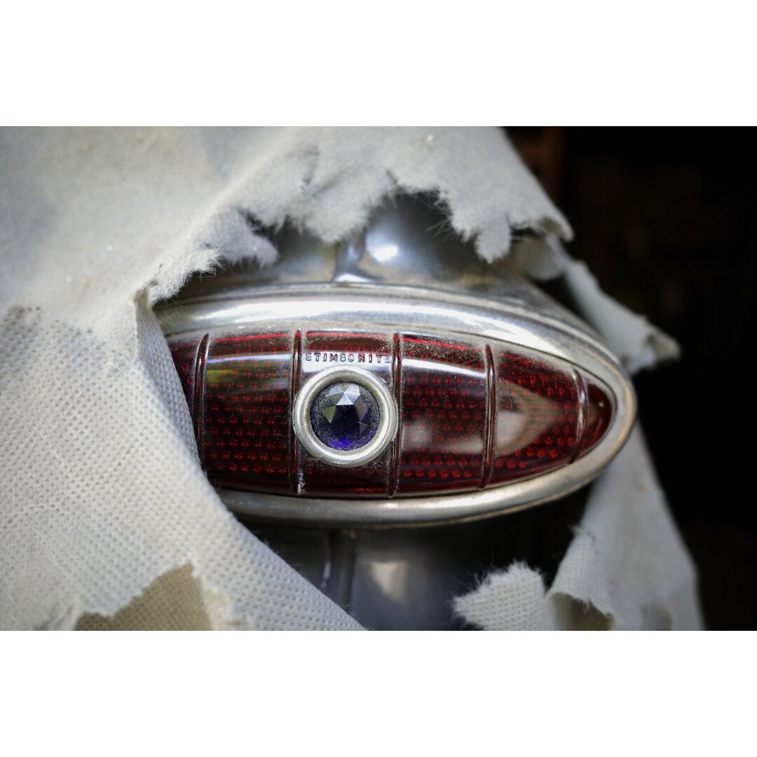 Blue dot tail light on a gray 1949 Ford sedan, poking through a hole in the car cover