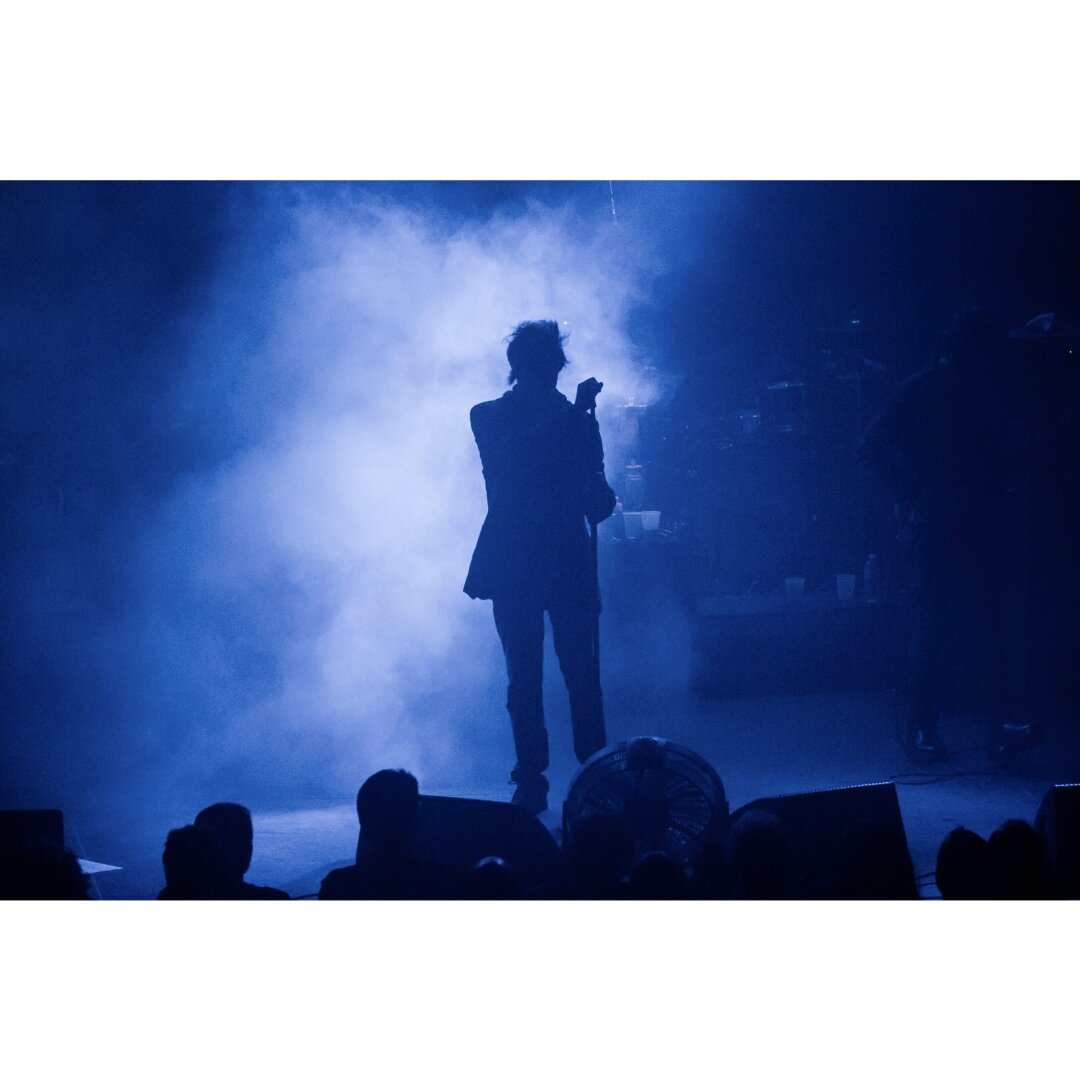 Ian McCulloch performing at an Echo and the Bunnymen show, at the Union Transfer in Philadelphia.  He is backlit by blue light on a mist filled stage.