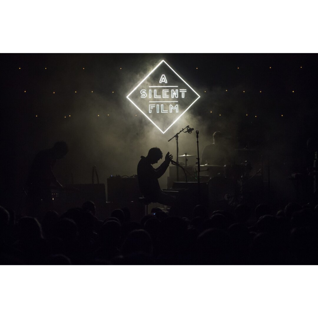 A band called “A Silent Film” performing at Union Transfer in Philadelphia.  Very dark with minimal illumination provided by their sign and some light mist in the air.