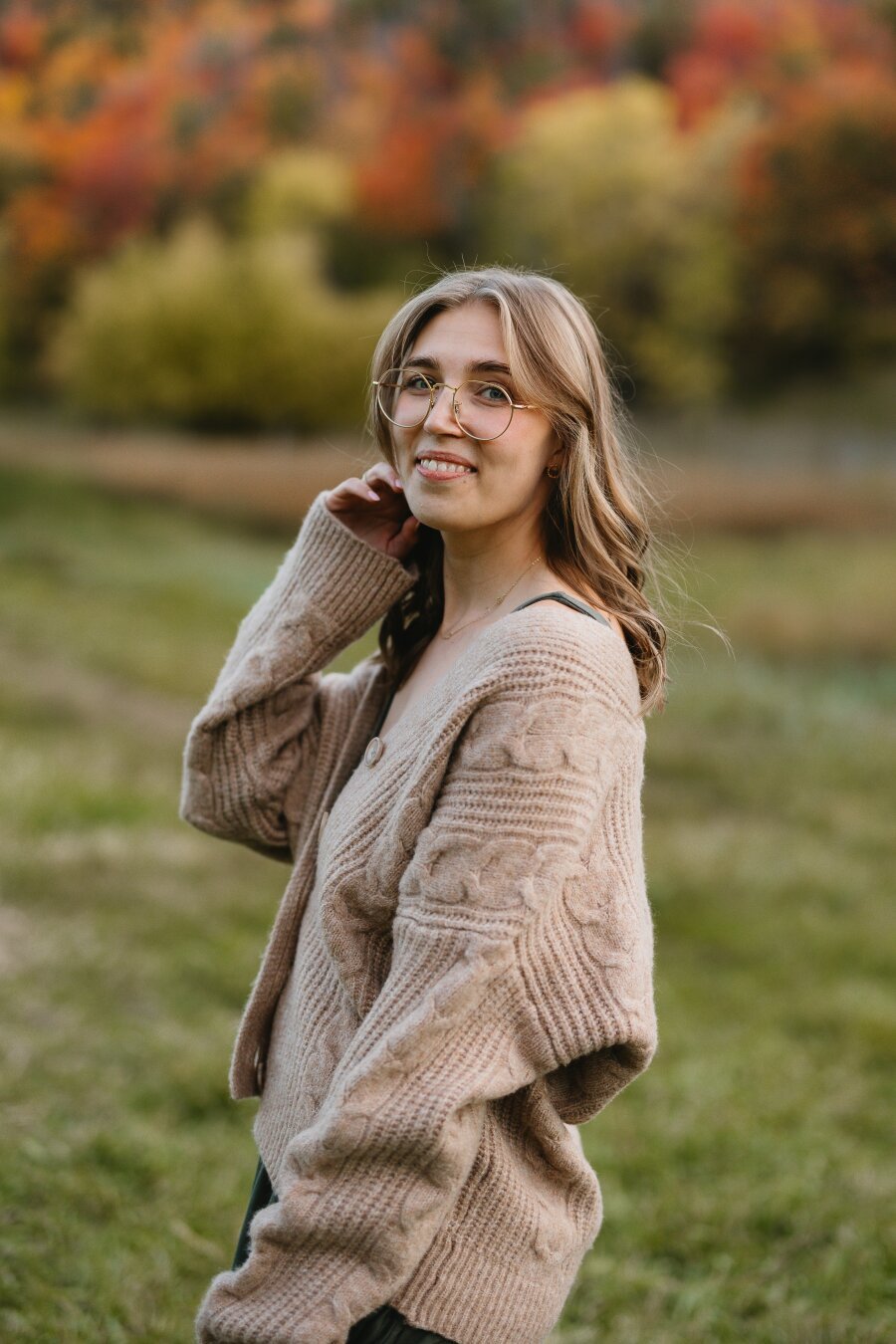 Jacqueline Wormington posing in a field in front of fall colored mountains.