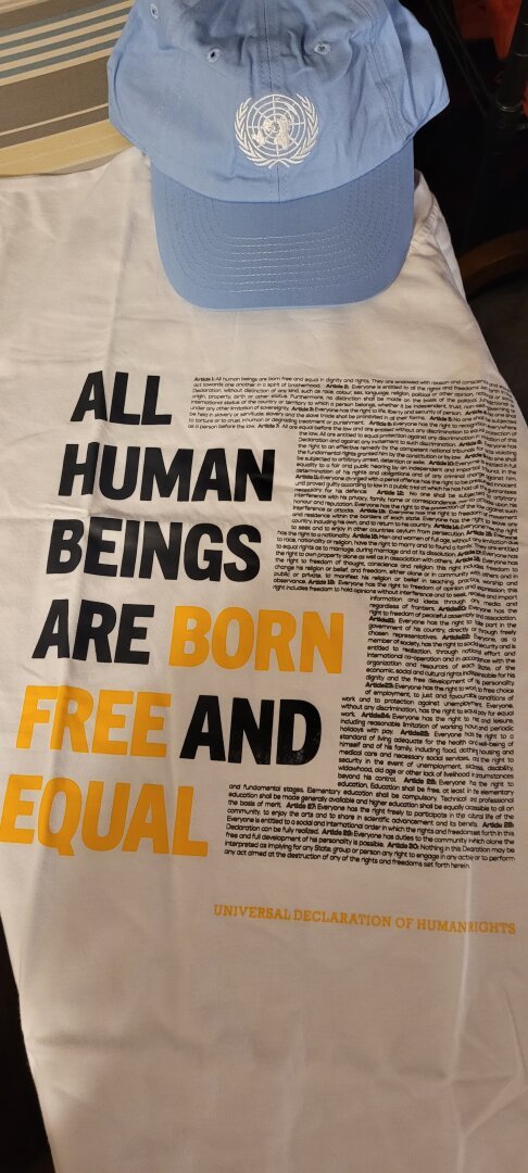 White t-shirt with the entire text of the Universal Declaration of Human Rights printed on the front, plus a light blue baseball hat with the United Nations emblem on it.