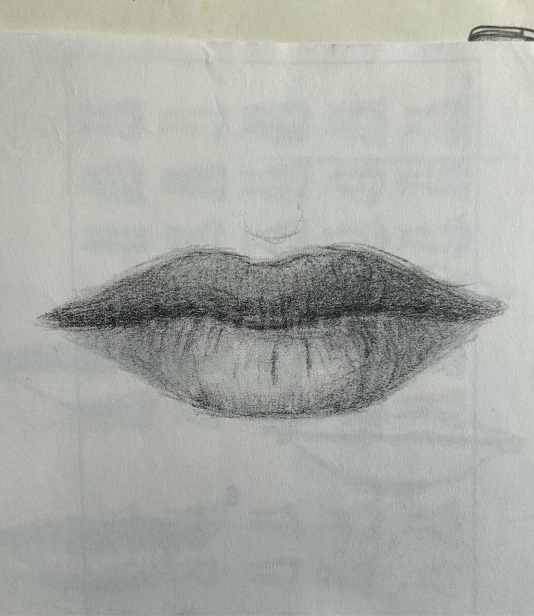 A pair of lips drawn using pencil on scrap paper