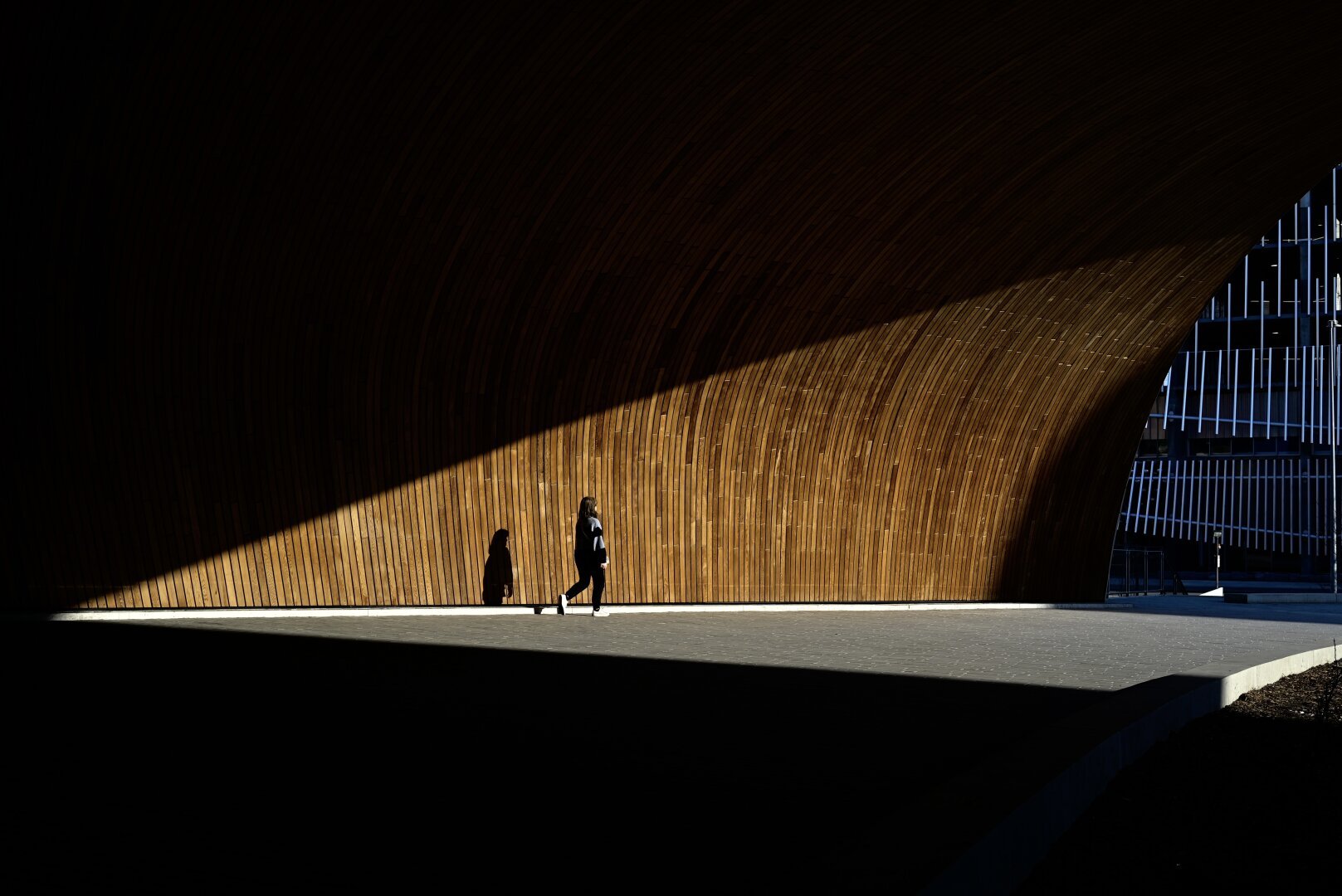 A triangle shape is formed by the sun against the Calgary library, which features a wooden surface, almost like a tunnel.