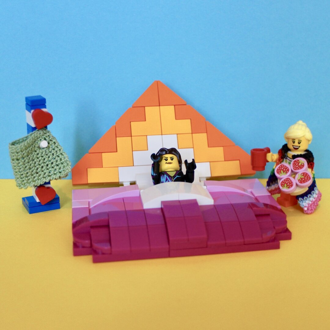 Orange white and pink lego built envelop with a minifig in it. Another minifig brings breakfast. Friesian coat hanger with a crocheted jacket.