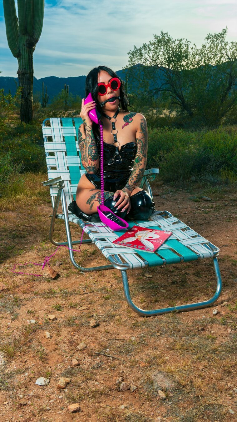 Model sitting on a lawn chair in the deserve talking on the phone