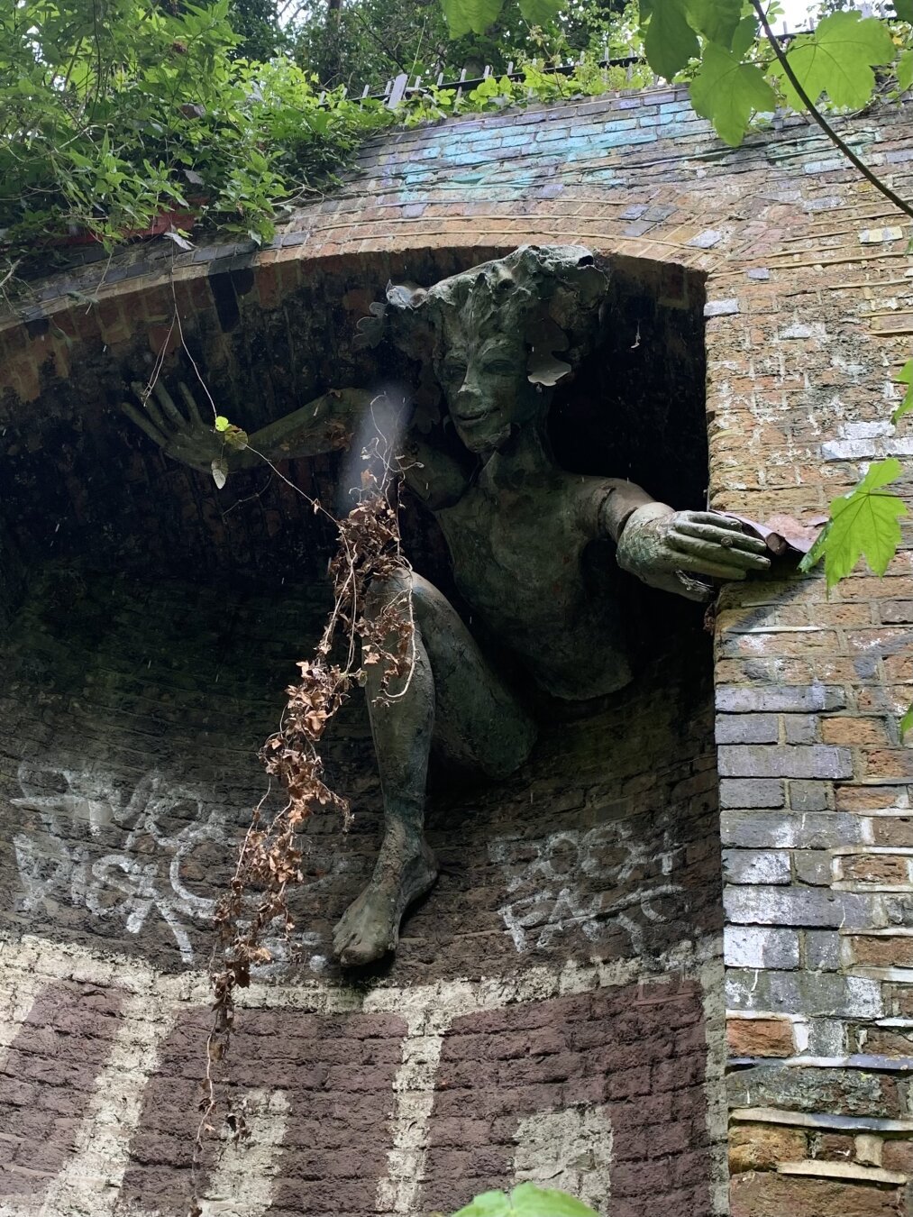 A pan like character climbing out of a railway siding which is overgrown and covered in ivy