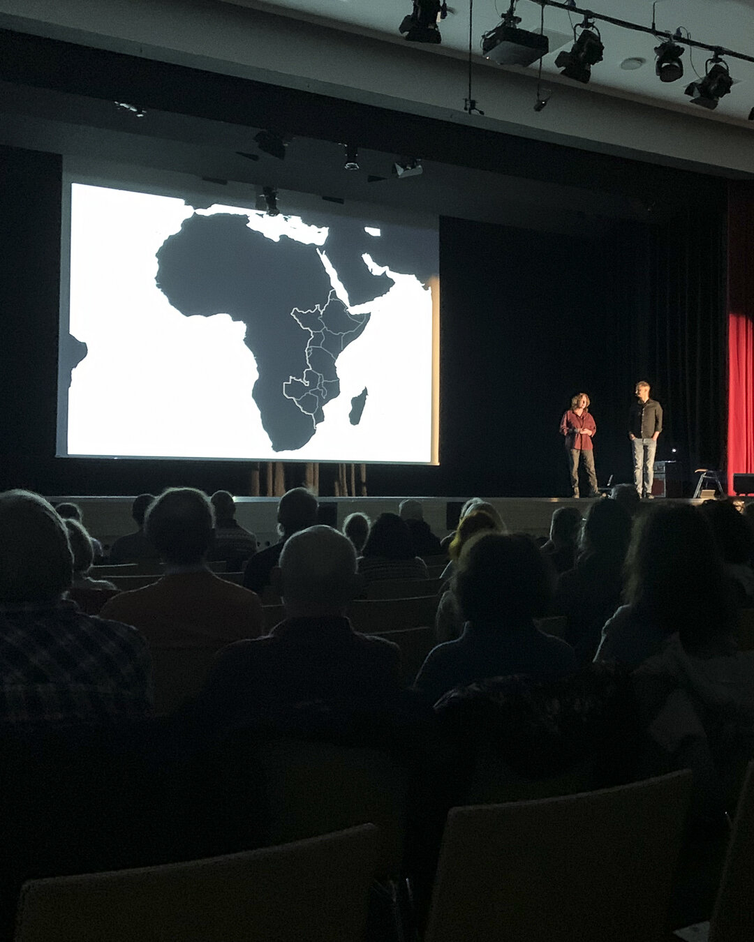 Jutta und Michael vor großer Leinwand und der Karte Ostafrikas