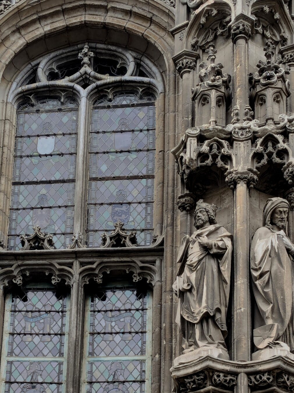 Statues on medieval gothic church near a stained glass window
