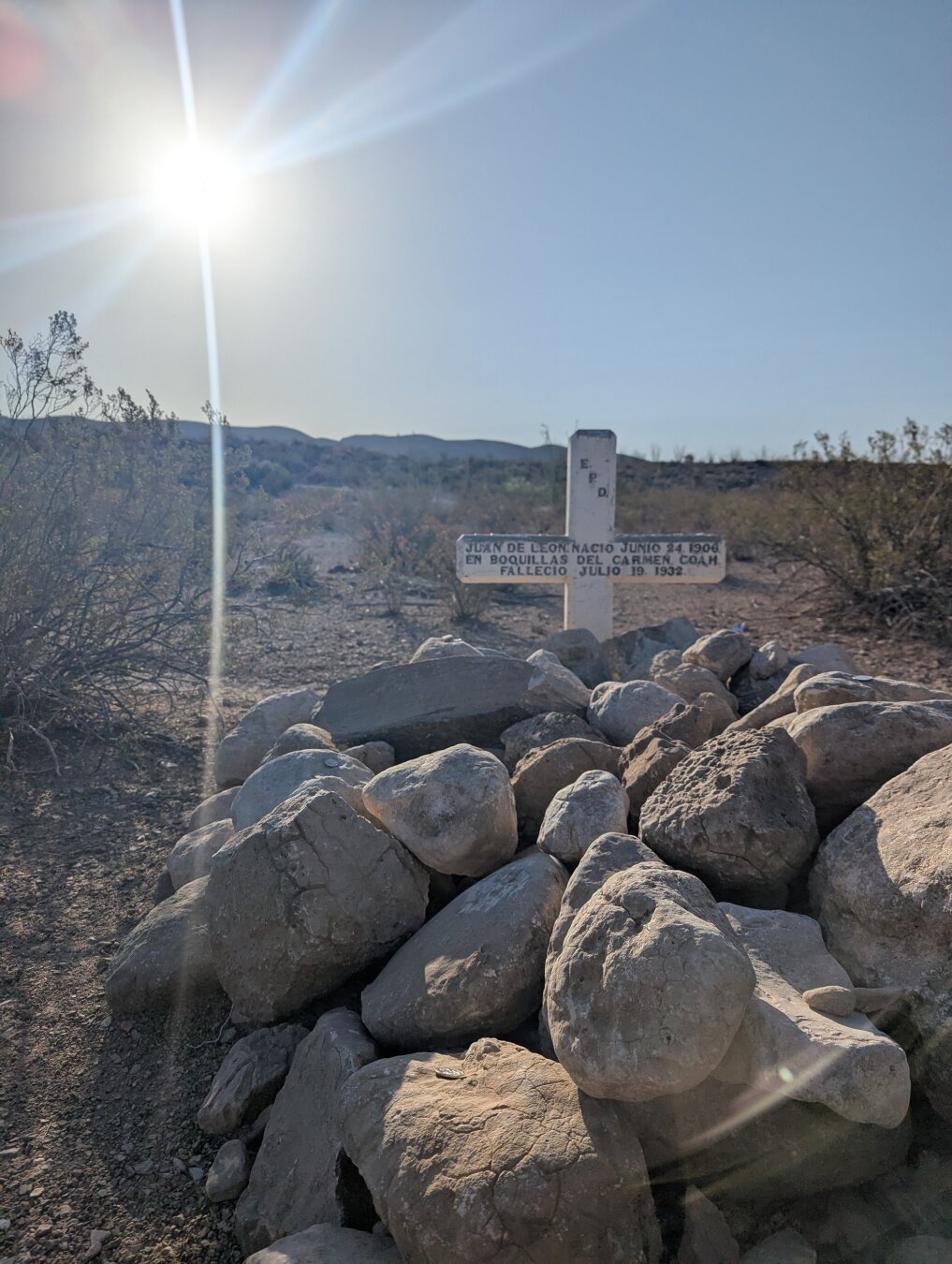 A gravestone in the desert, with rocks stacked above the body.