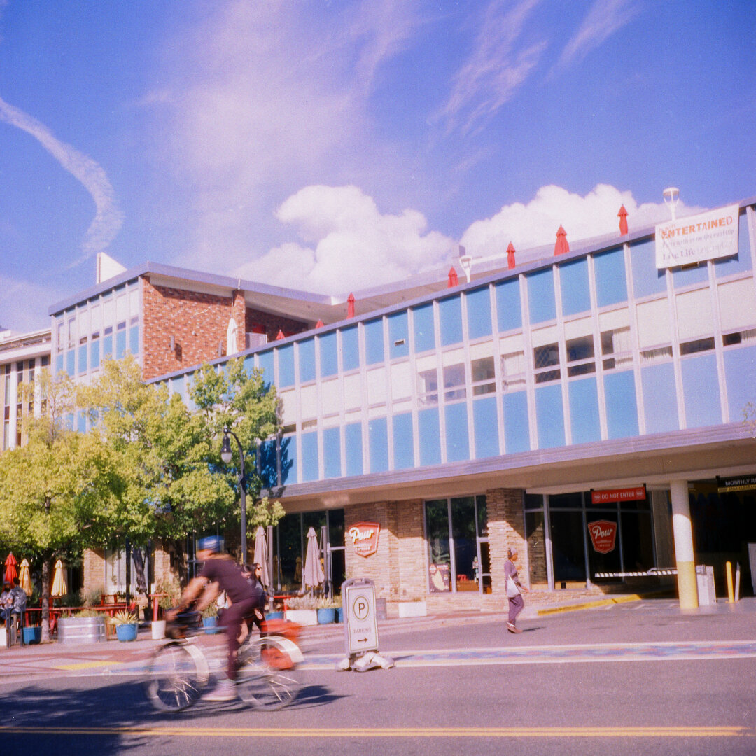 blue building with blue sky and clouds, bicyclist in foreground