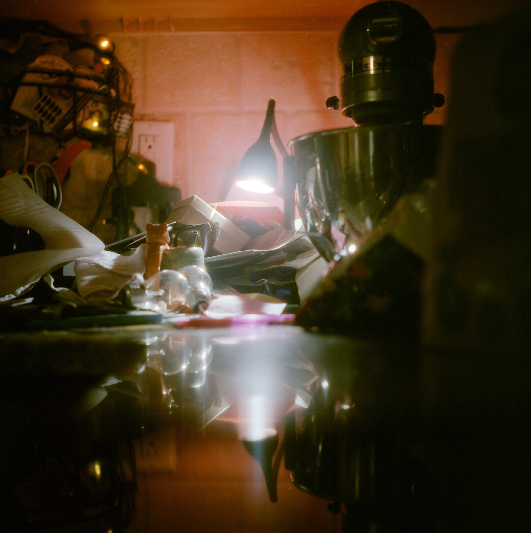 kitchen still life: KitchenAid blender, lamp, light bulbs, bag of chips, string lights, plastic animal with ears