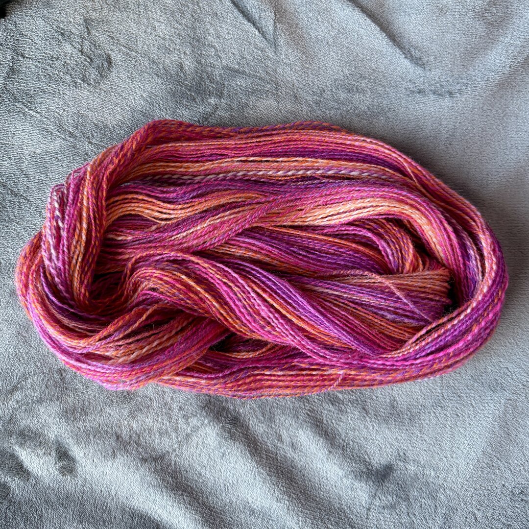 2 ply handspun yarn with hot pink, purple, orange, and white colors intermingled together.