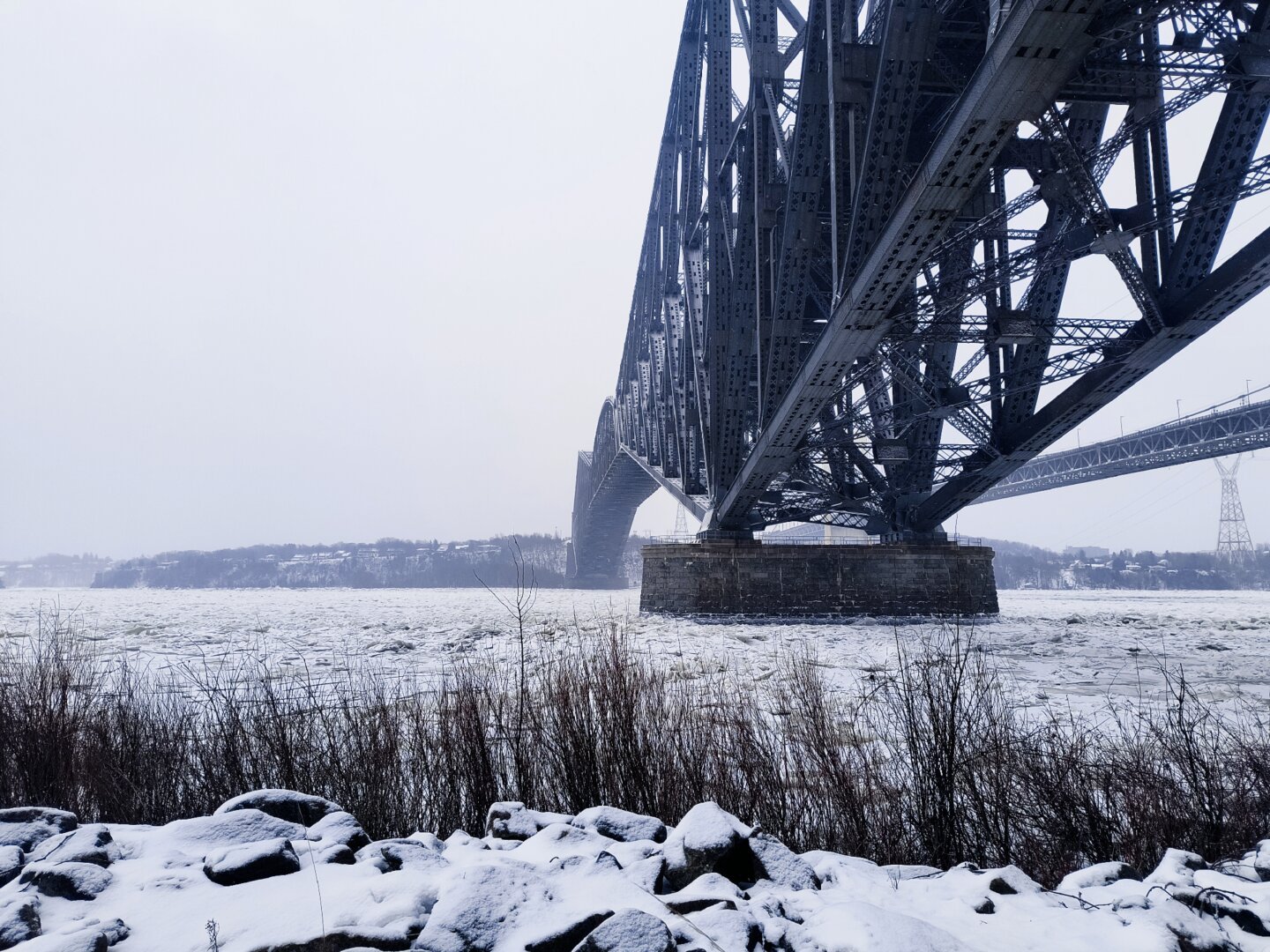 Vista del puente de Québec, en remache de acero, desde la Promenade Champlain al borde norte del San Lorenzo -a medias congelado- en la ciudad de Québec. Del otro lado del río, la ciudad de Lévis.