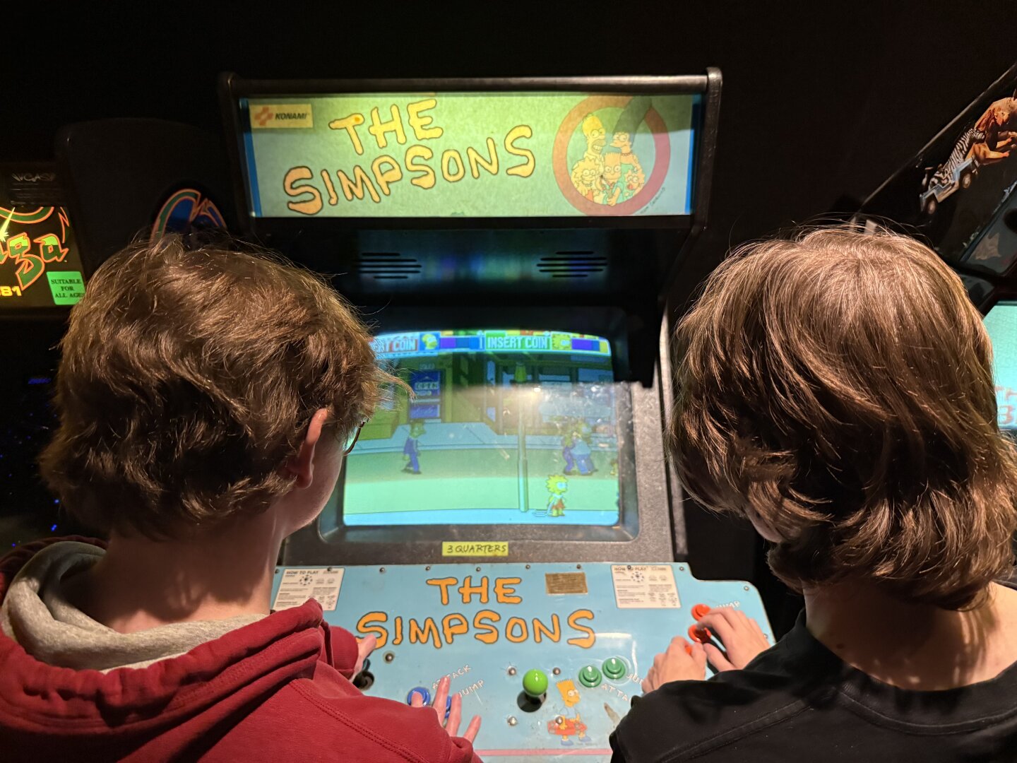 Two dudes playing the Simpsons arcade game