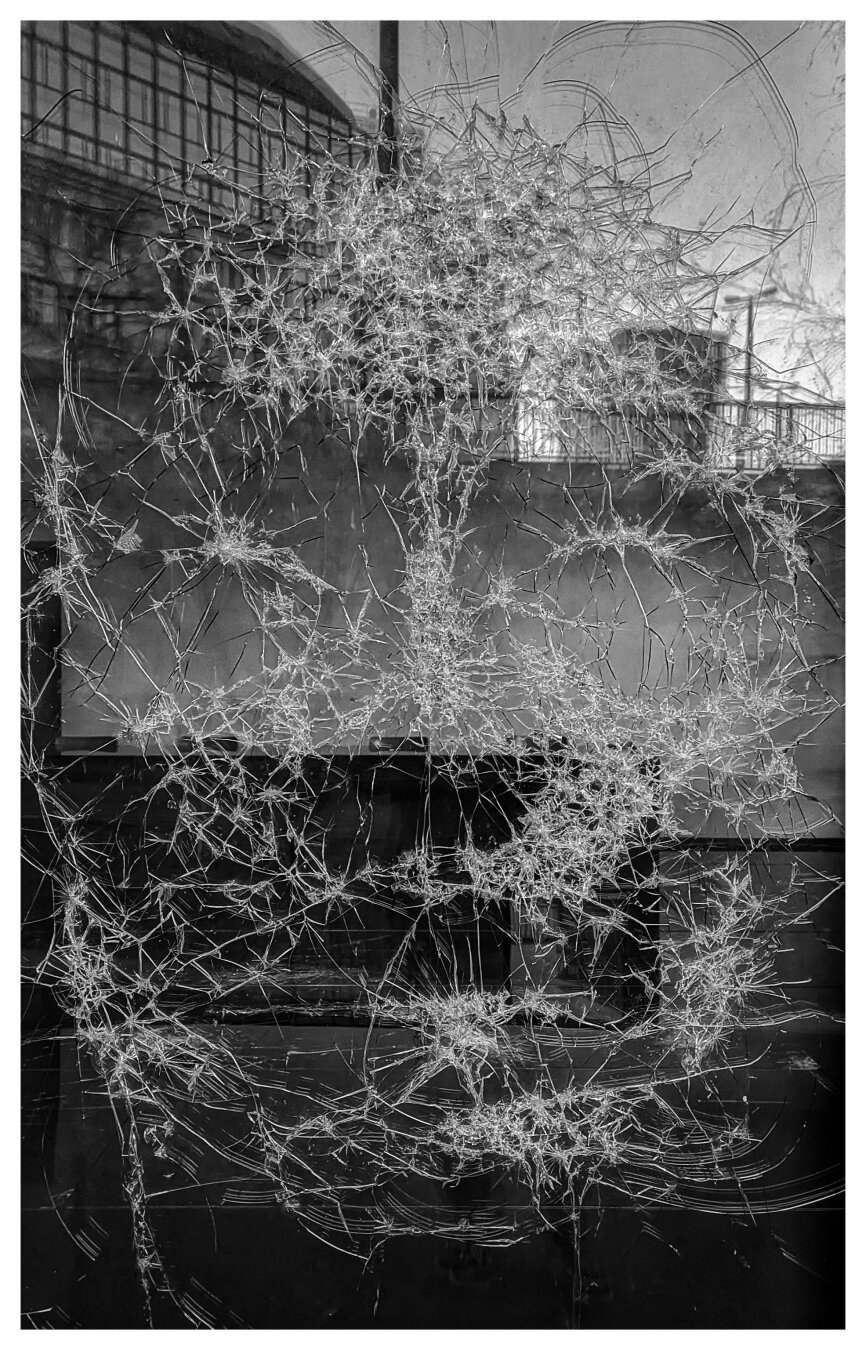 Photo of an atelier window, where the artist has hammered a female face into the glass.